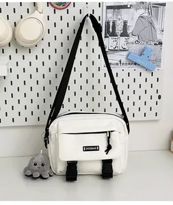 Detailed view of white canvas crossbody bag with black buckles and octopus charm