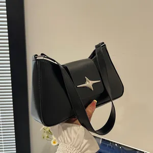 Détail du sac baguette en similicuir noir avec étoile argentée et bandoulière élégante