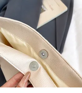 Vue détaillée de la boucle magnétique argentée et des coutures sur le sac seau en cuir crème