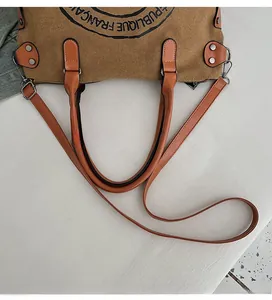 Detailed view of canvas tote bag with adjustable leather strap and vintage printed seal