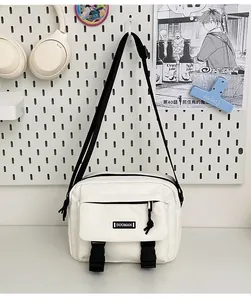 Detail of white canvas crossbody bag with black adjustable strap and buckle closure