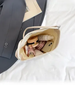 Vue de dessus montrant l'intérieur spacieux et le cuir grainé souple du sac seau crème