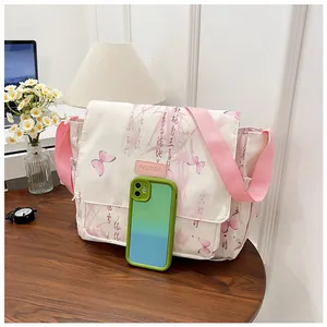 Close-up of white floral crossbody bag with pink butterfly print and smartphone for scale