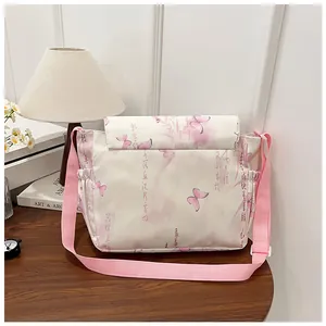 Detail of floral butterfly print crossbody bag with pink strap on wooden table