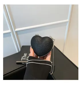 Gros plan d'un sac cœur noir scintillant avec chaîne en argent porté à la main