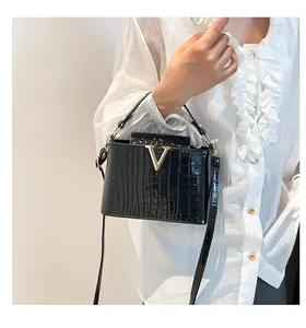 Close-up of black crocodile pattern leather handbag with gold V-shape metal hardware