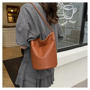 Lifestyle view of a caramel leather bucket bag with pebble texture and slim strap