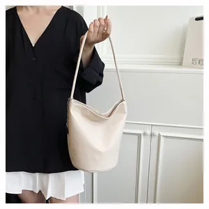 Detail of soft cream leather bucket bag with silver chain strap and lychee texture