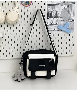 Detail of canvas messenger bag with contrast panels, buckle closure, and plush charm
