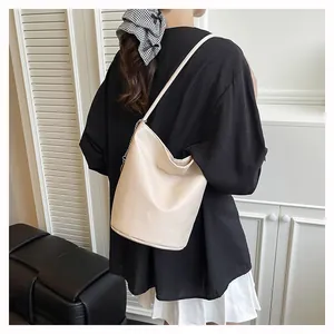 Model showing a creamy white bucket bag with pebble grain faux leather and chain detail
