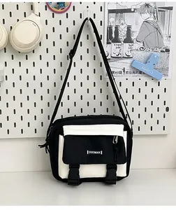 Detail of a black and white canvas crossbody bag with double buckle flap and front pocket