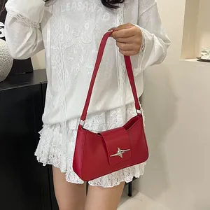 Détail d'un sac à bandoulière rouge en similicuir avec boucle étoile argentée sur modèle