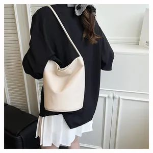 Détail du sac seau crème avec texture grainée porté par un mannequin pour le travail