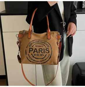 Detail of vintage canvas tote bag featuring brown fabric and orange leather straps
