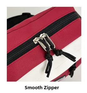 Close-up of smooth double metal zippers and red-white canvas texture on the crossbody bag
