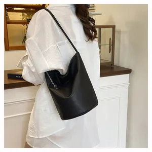 Detail of black pebbled leather bucket bag with silver metal chain accent on side