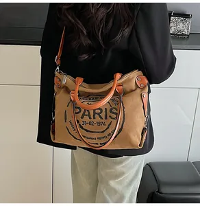Detail of vintage canvas tote bag showing the PARIS letter print and leather handle details