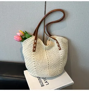 Detail of woven straw tote bag featuring brown leather handles and decorative tulips
