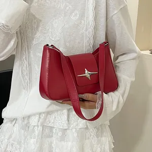 Détail du sac à bandoulière rouge en demi-lune avec une boucle en métal argenté en étoile