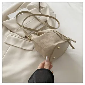 Close-up of beige suede bucket bag detail with golden studs and drawstring closure