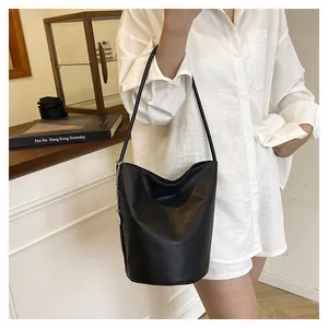 Detail of soft black pebble leather bucket bag with silver chain on model's shoulder