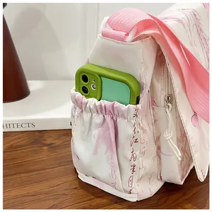 Close-up of the side pocket on a white floral crossbody bag holding a smartphone