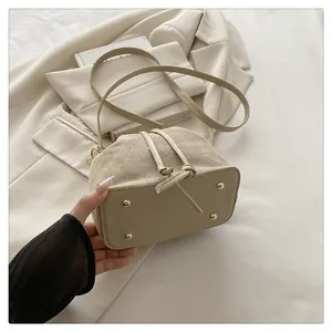 Detailed close-up of canvas bucket bag base with protective gold studs and leather trim