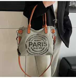 Detail of grey canvas tote bag with brown leather handles and vintage Paris logo