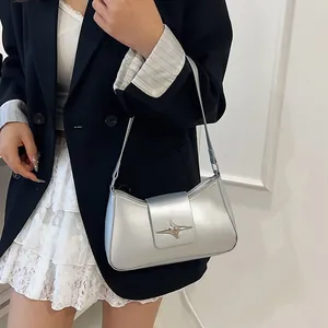 Détail d'un sac à bandoulière argenté avec boucle étoile, porté par un mannequin en studio