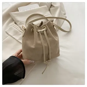 Close-up of beige drawstring bucket bag featuring golden eyelets and soft suede texture