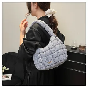 Détail du sac à épaule bouffant matelassé bleu clair porté par un mannequin élégant