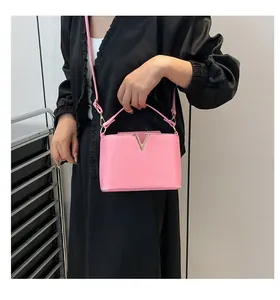 Détail d'un sac à main rose en cuir avec boucle en métal doré en V et poignée chic