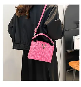 Detail of rose pink crocodile pattern handbag with gold V-shaped buckle and strap
