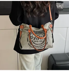 Detailed back view of a large vintage canvas tote bag with leather straps on a model