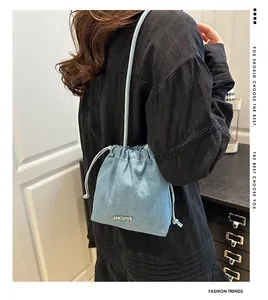 Close-up of light blue denim bucket bag with JINGPIN metal logo and drawstring detail