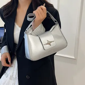 Détail du sac sous le bras argenté avec boucle moderne en forme d'étoile et texture fine