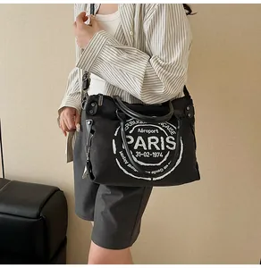 Close-up of black canvas tote bag featuring vintage Paris airport graphic with leather handles
