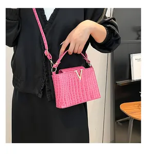 Detail of pink croc-embossed tote bag featuring a gold V-shaped metal lock on the front