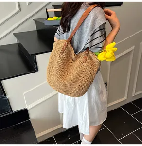 Detail of woven straw tote bag with brown leather handles and textured V-shape pattern