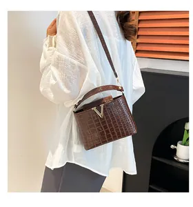 Close-up of brown croc-effect handbag featuring a luxury gold V-shaped metal buckle detail