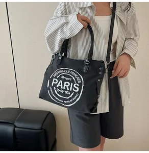 Detail of black canvas tote bag showing the PARIS badge print and detachable shoulder strap