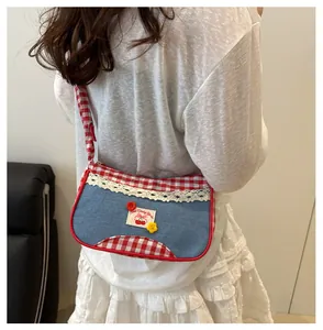 Detail of denim bag featuring cherry label, lace trim, and red checkered stitching