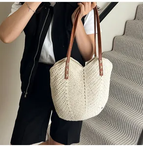 Detail of cream woven tote bag featuring textured V-pattern and brown leather shoulder straps