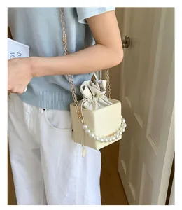 Detail der cremefarbenen Mini-Webtasche mit großem Perlengriff und goldener Kette