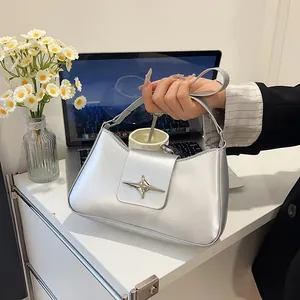 Sac à main argenté métallisé en demi-lune avec boucle étoile sur un bureau élégant