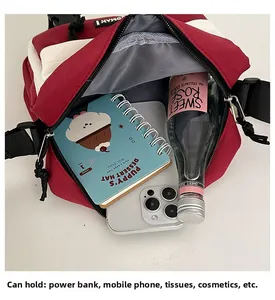 Detail view of the spacious red and white crossbody bag showing phone and notebook storage