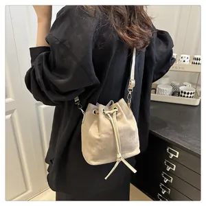 Detail of beige microfiber bucket bag showing drawstring closure and sleek metal hardware