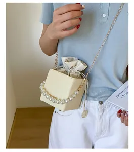Detailed texture of off-white woven bucket bag with large pearl handle and gold chain