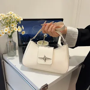 Sac baguette élégant en cuir crème avec boucle étoile argentée sur un bureau blanc