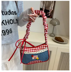 Detail of red gingham and denim handbag with lace trim and cherry patch